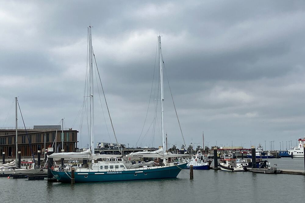 Zeilschepen en vissersboten liggen afgemeerd in de haven van Lauwersoog voor een donker havengebouw